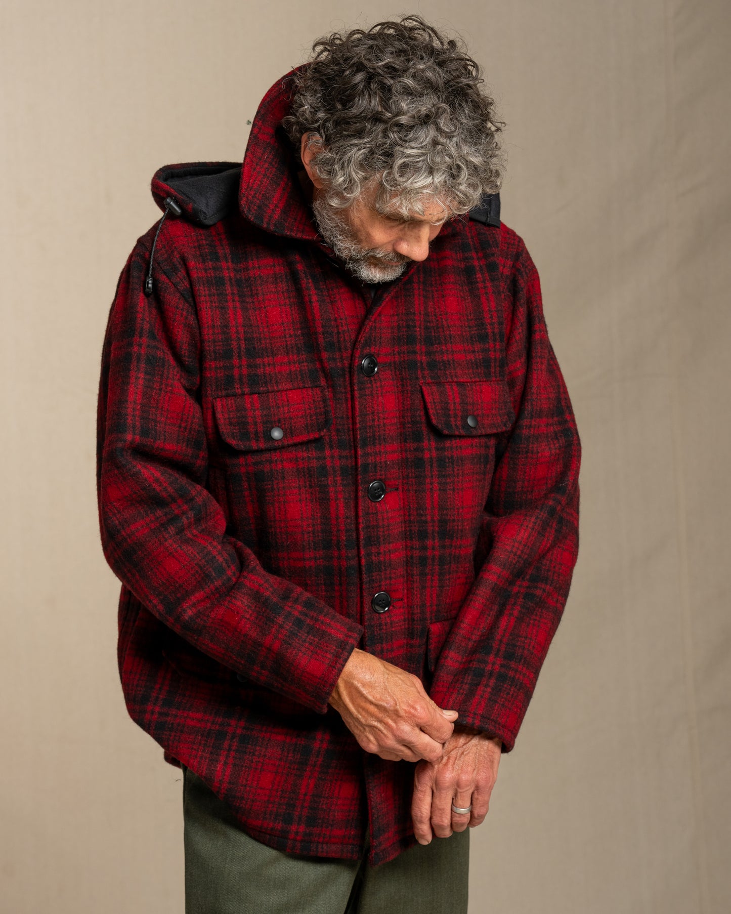 Man wearing a red plaid wool jacket against a beige background