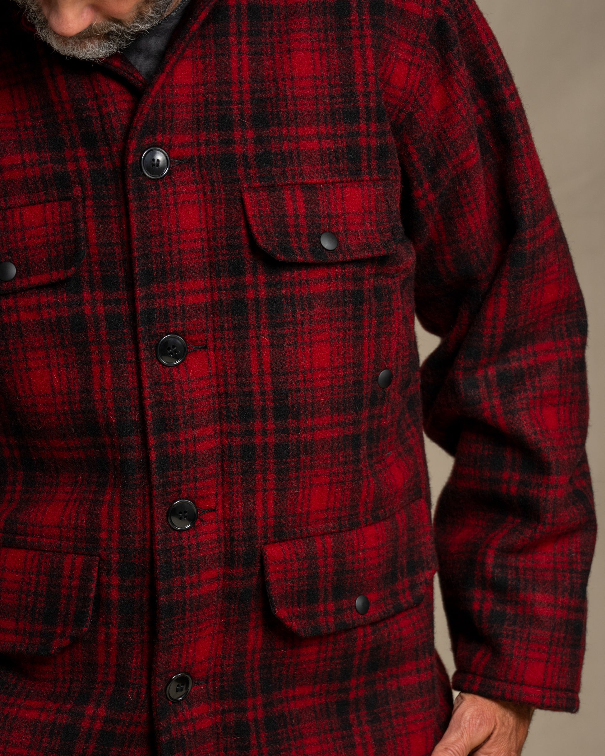 Red and black plaid jacket with buttons on a neutral background