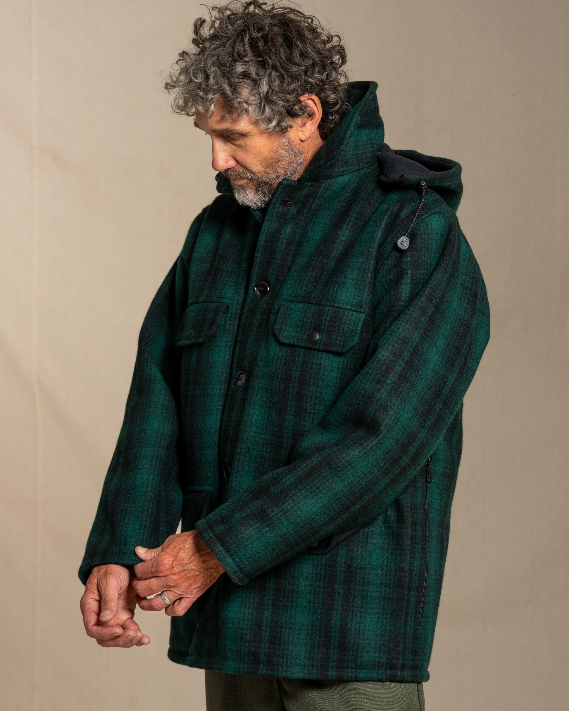 Man wearing a green plaid wool jacket and pants against a beige background