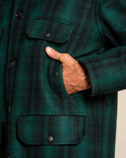Close-up of a person wearing a green plaid jacket with a hand in the pocket.