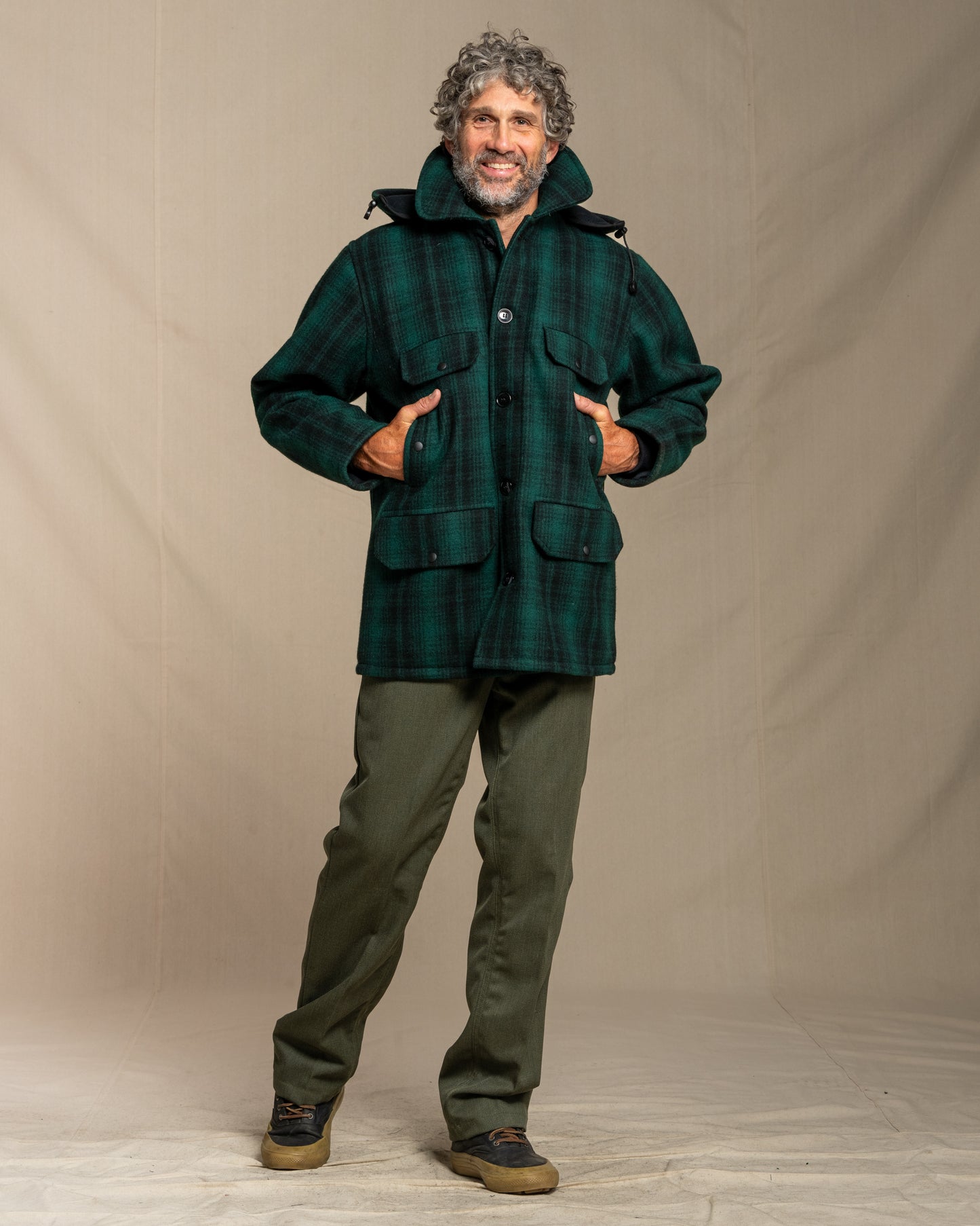 Man wearing a green plaid jacket and pants against a beige background