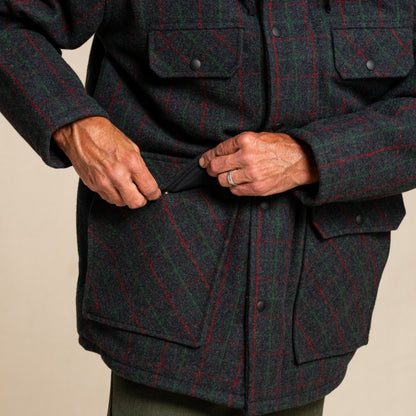 Person wearing a dark green and red plaid jacket on a beige background
