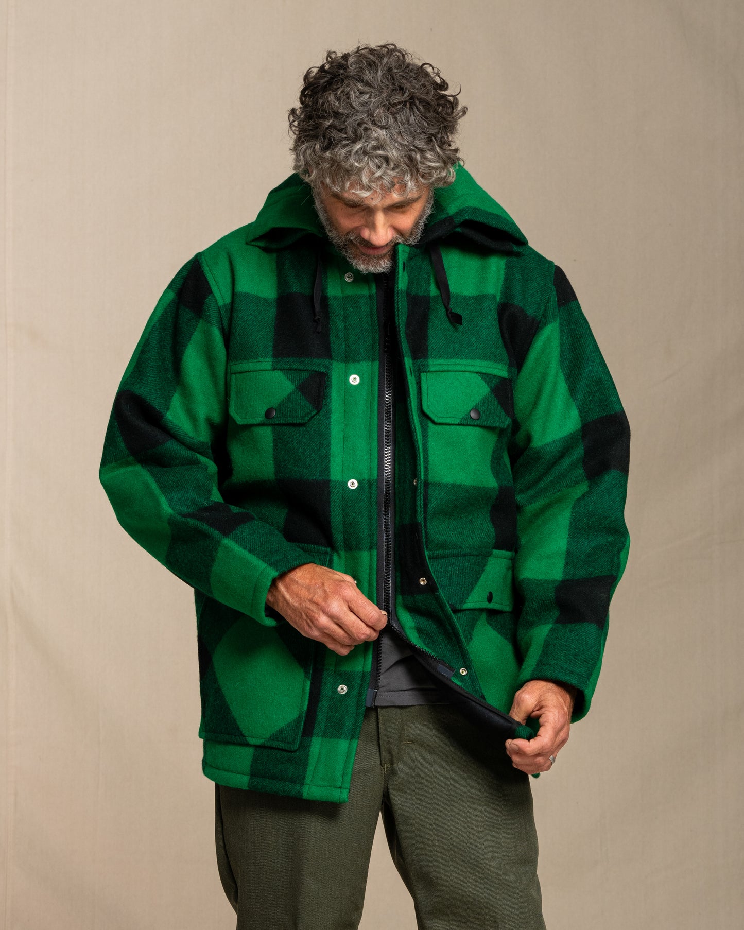 Man wearing a green and black checkered jacket against a beige background