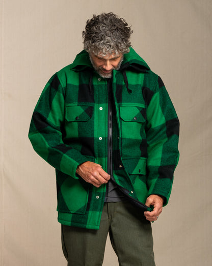 Man wearing a green and black checkered jacket against a beige background