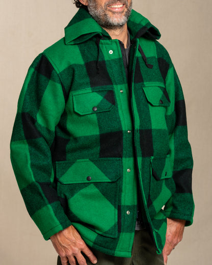 Person wearing a green and black checkered jacket against a beige background