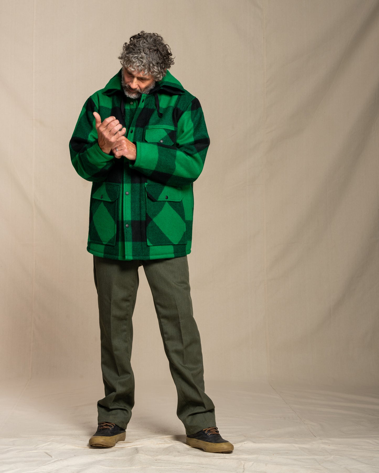 Man wearing a green plaid jacket against a beige background