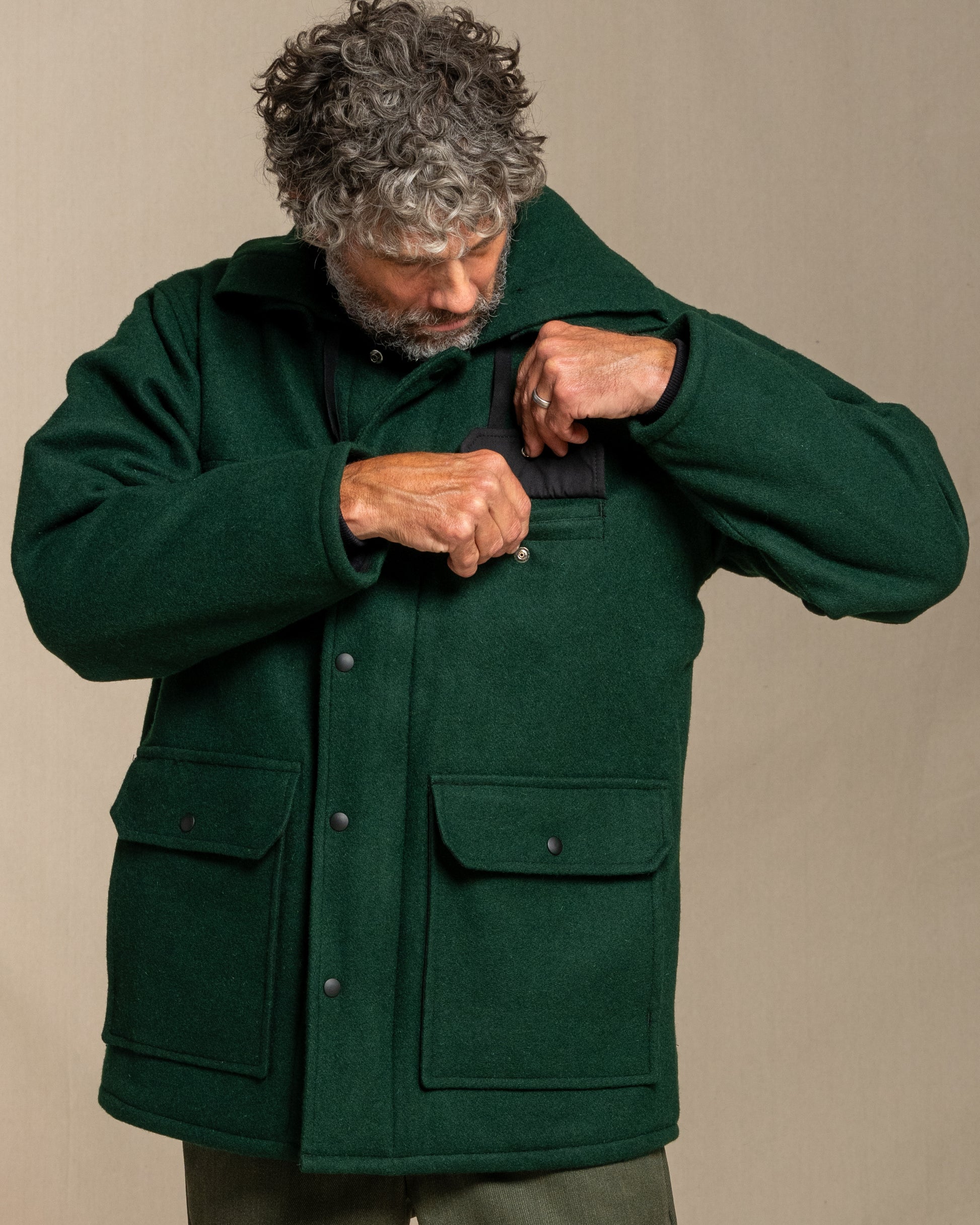 Man wearing a green coat against a beige background