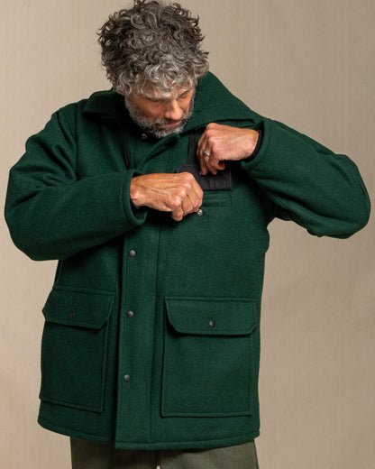 Man wearing a green coat against a beige background