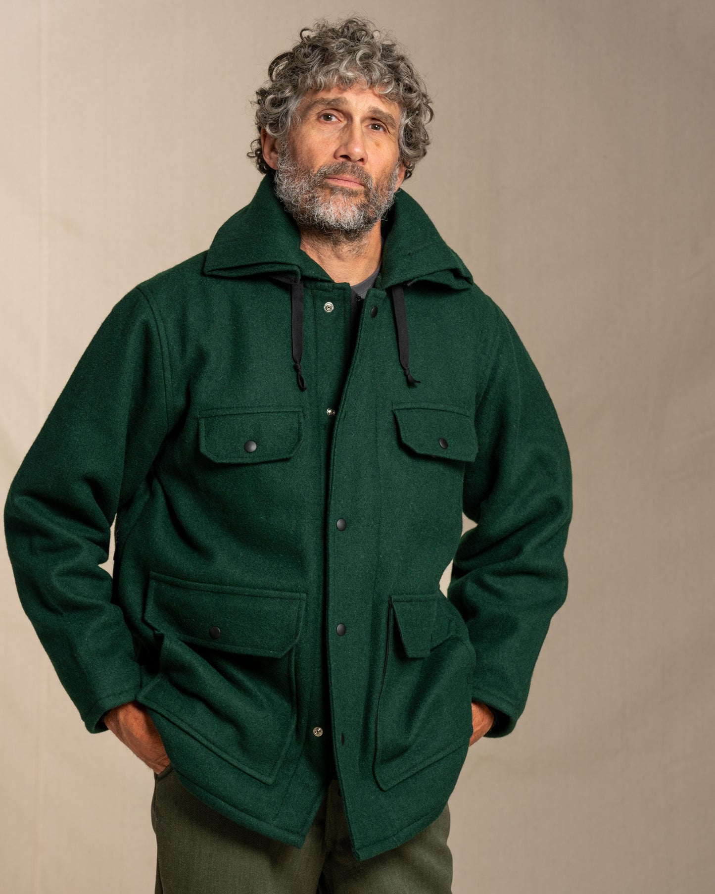 Man wearing a green wool jacket against a beige background
