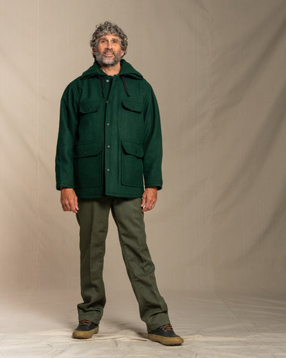 Man wearing a green coat and pants against a plain background