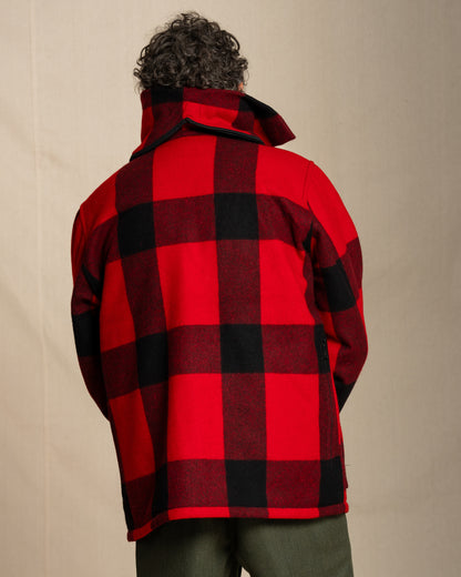 Person wearing a red and black checkered jacket against a beige background