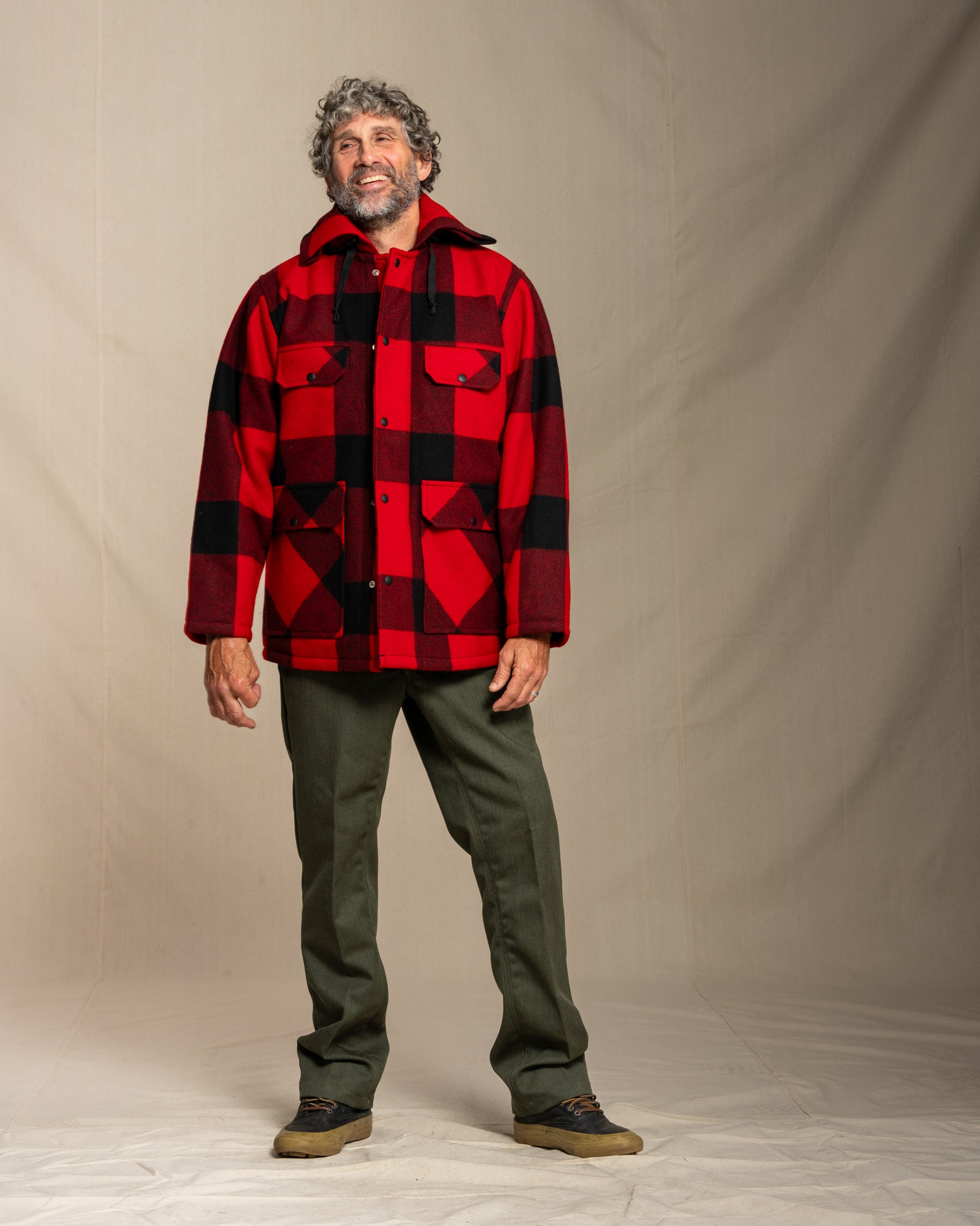 Man wearing a red and black checkered jacket against a plain background