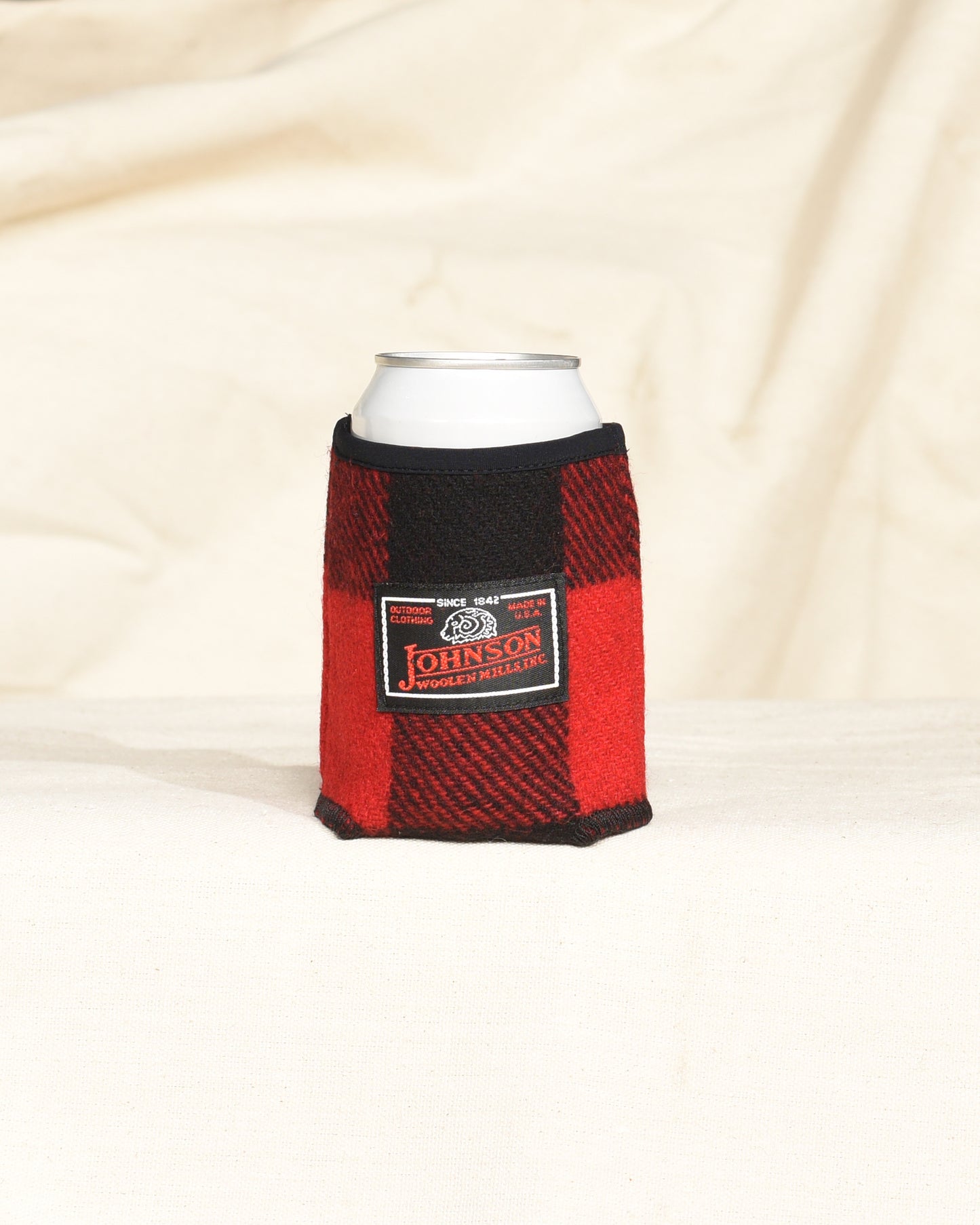 Red and black checkered can cooler with a label on a beige background