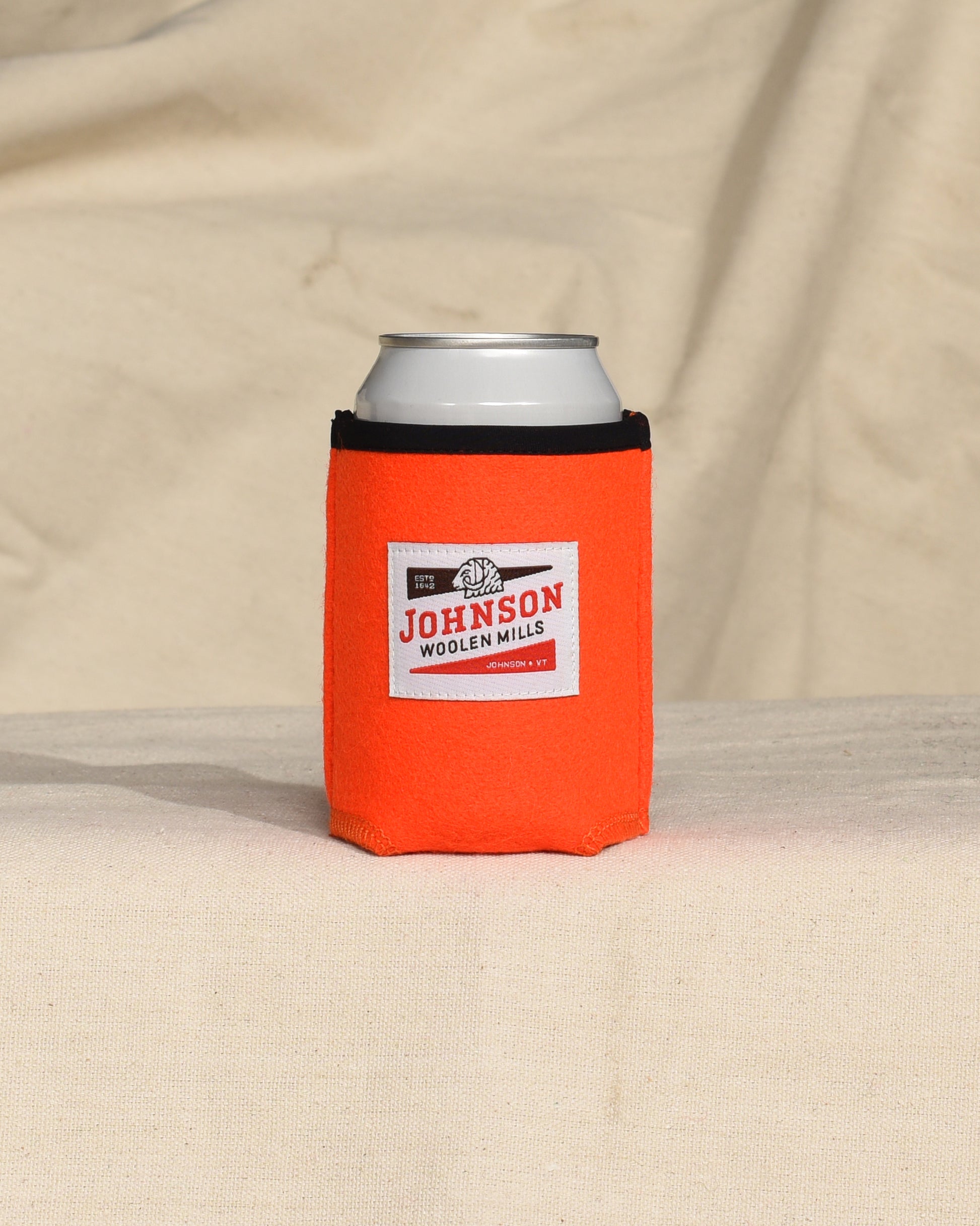 Blaze Orange wool can cooler with Johnson logo on a beige surface