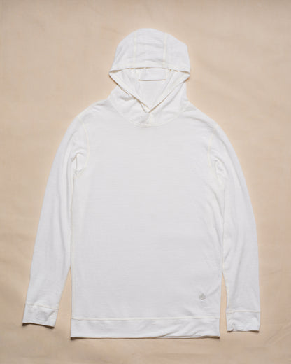 A white merino wool long-sleeve hooded top laid flat on a light beige background.