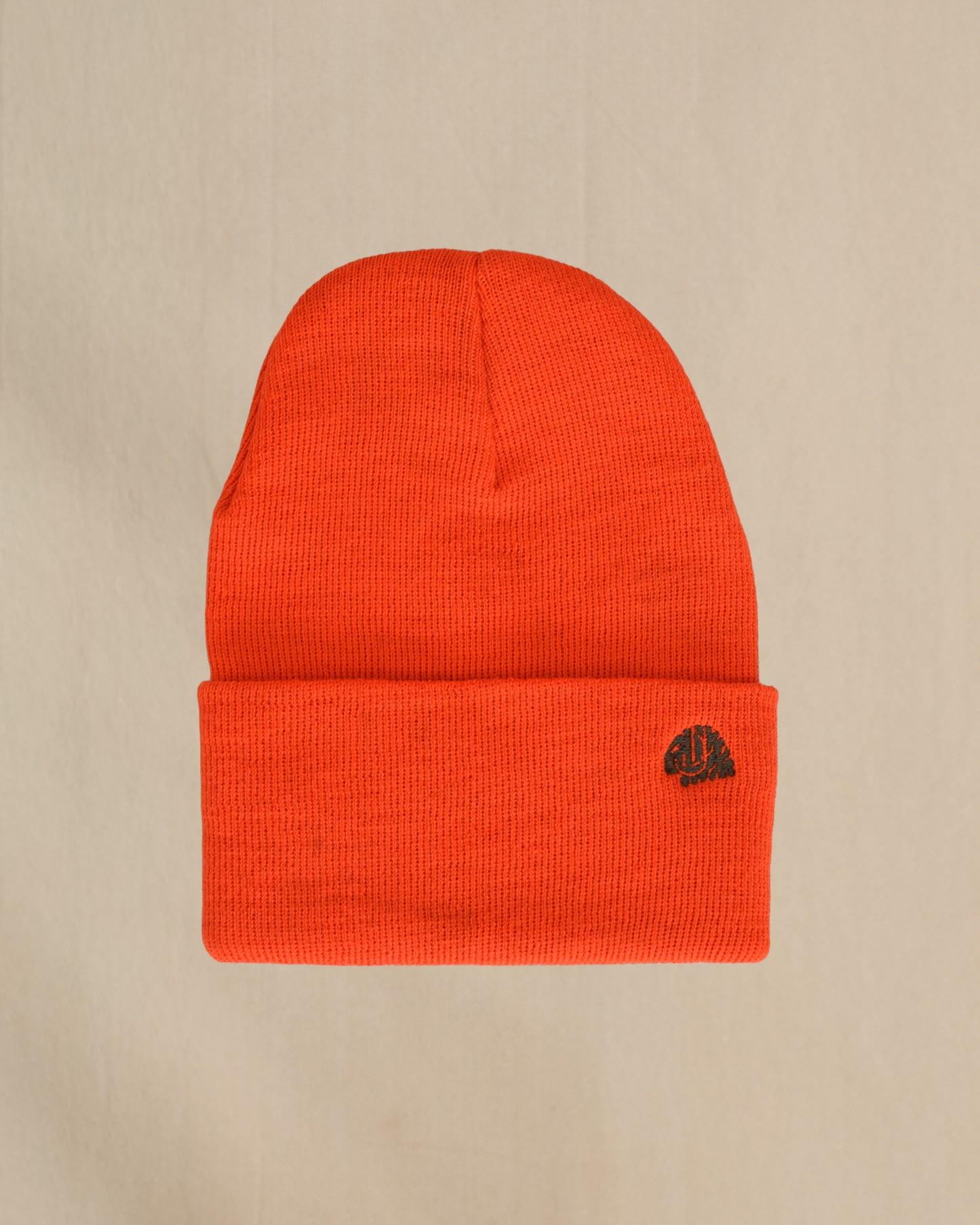 Merino Wool Blaze Orange beanie with a embroidered sheep on a beige background
