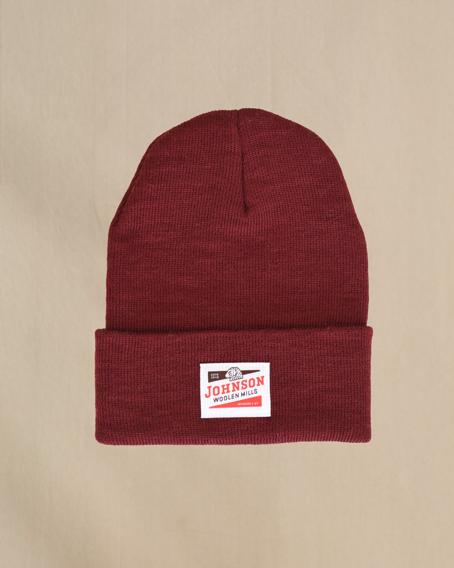 Maroon merino wool beanie with a Johnson label on a beige background