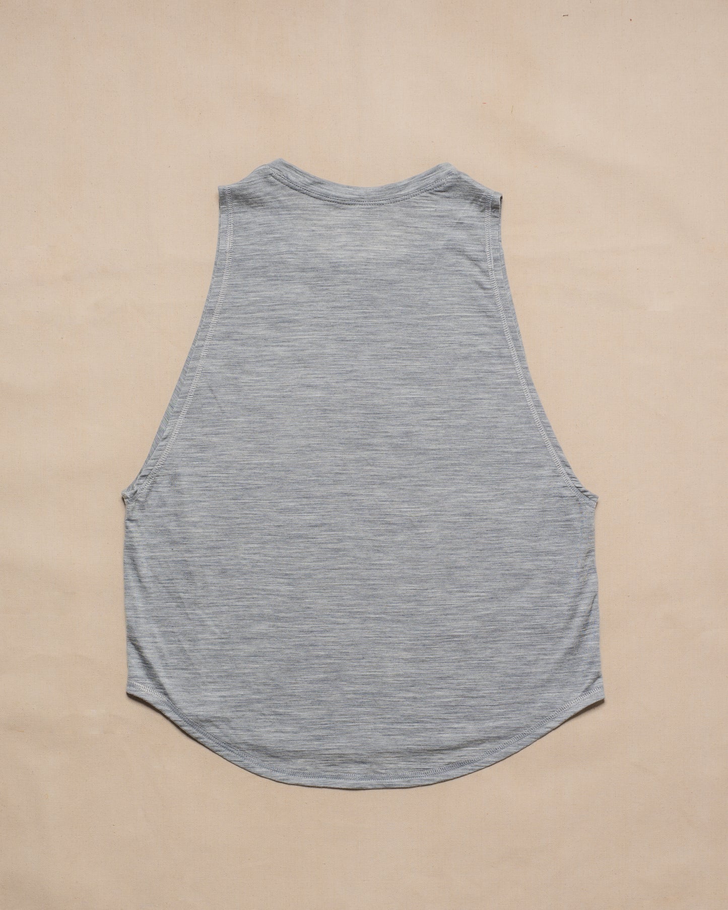 A gray sleeveless merino wool tank top laid flat face down on a light beige background.
