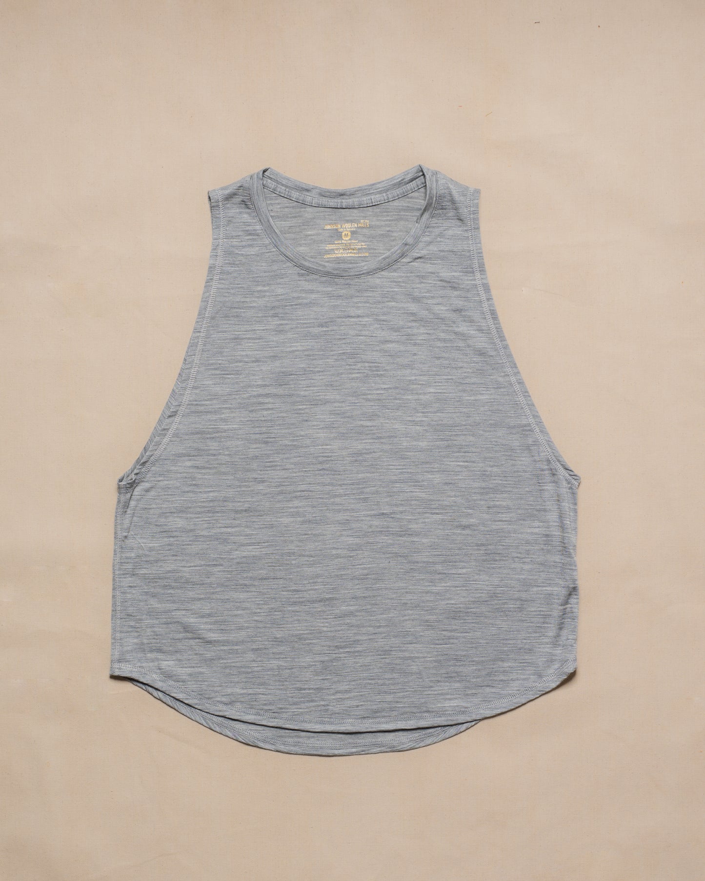 A gray sleeveless merino wool tank top laid flat on a light beige background.