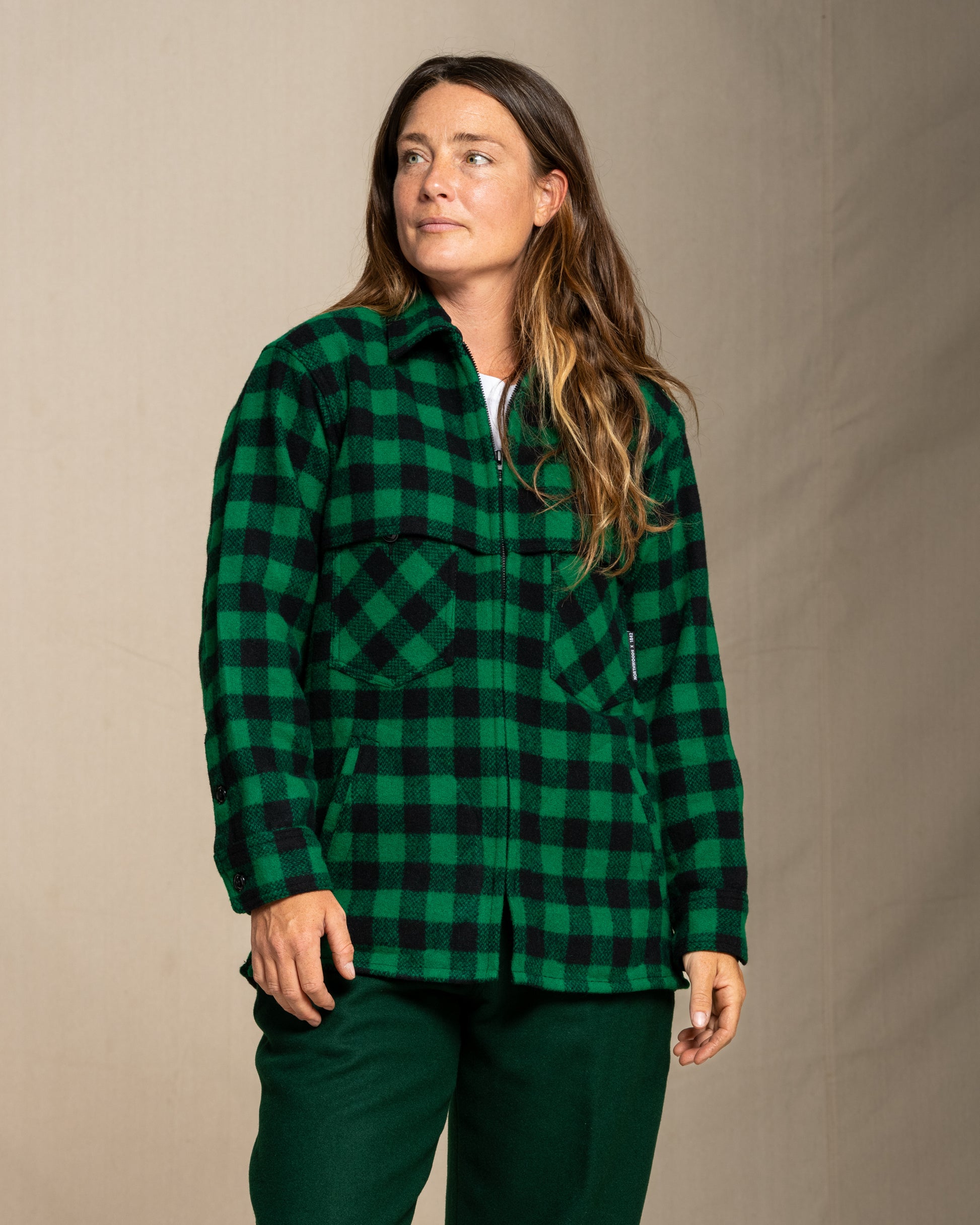 Woman wearing a green and black checkered wool jac shirt against a beige background