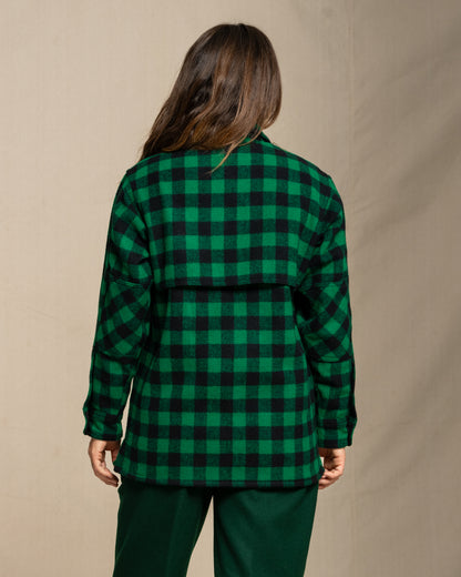 Woman wearing a green and black checkered wool jac shirt against a beige background