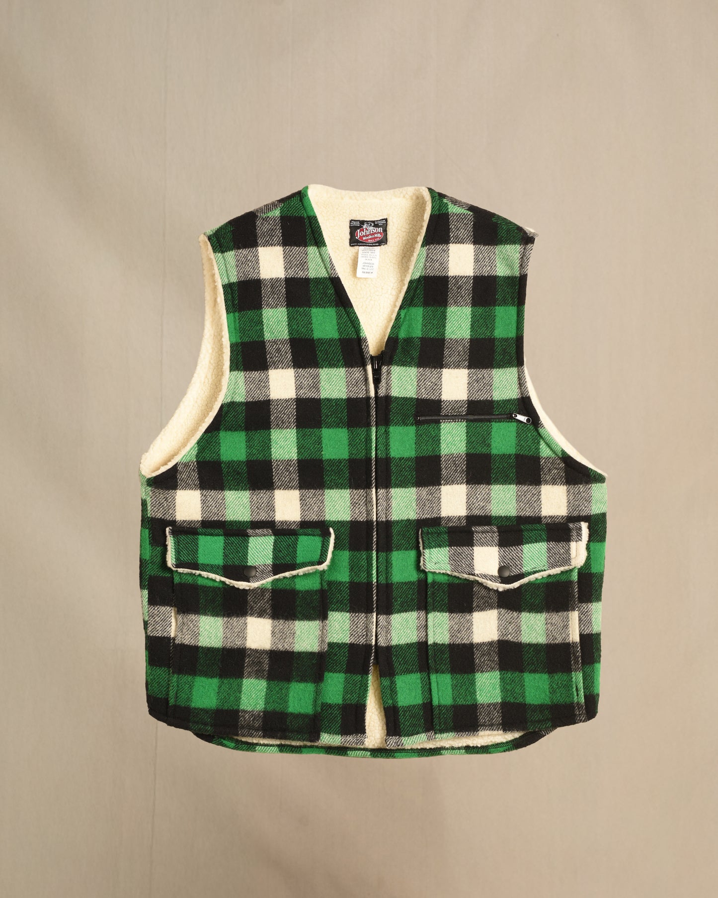 Green and black checkered sherpa vest on a beige background