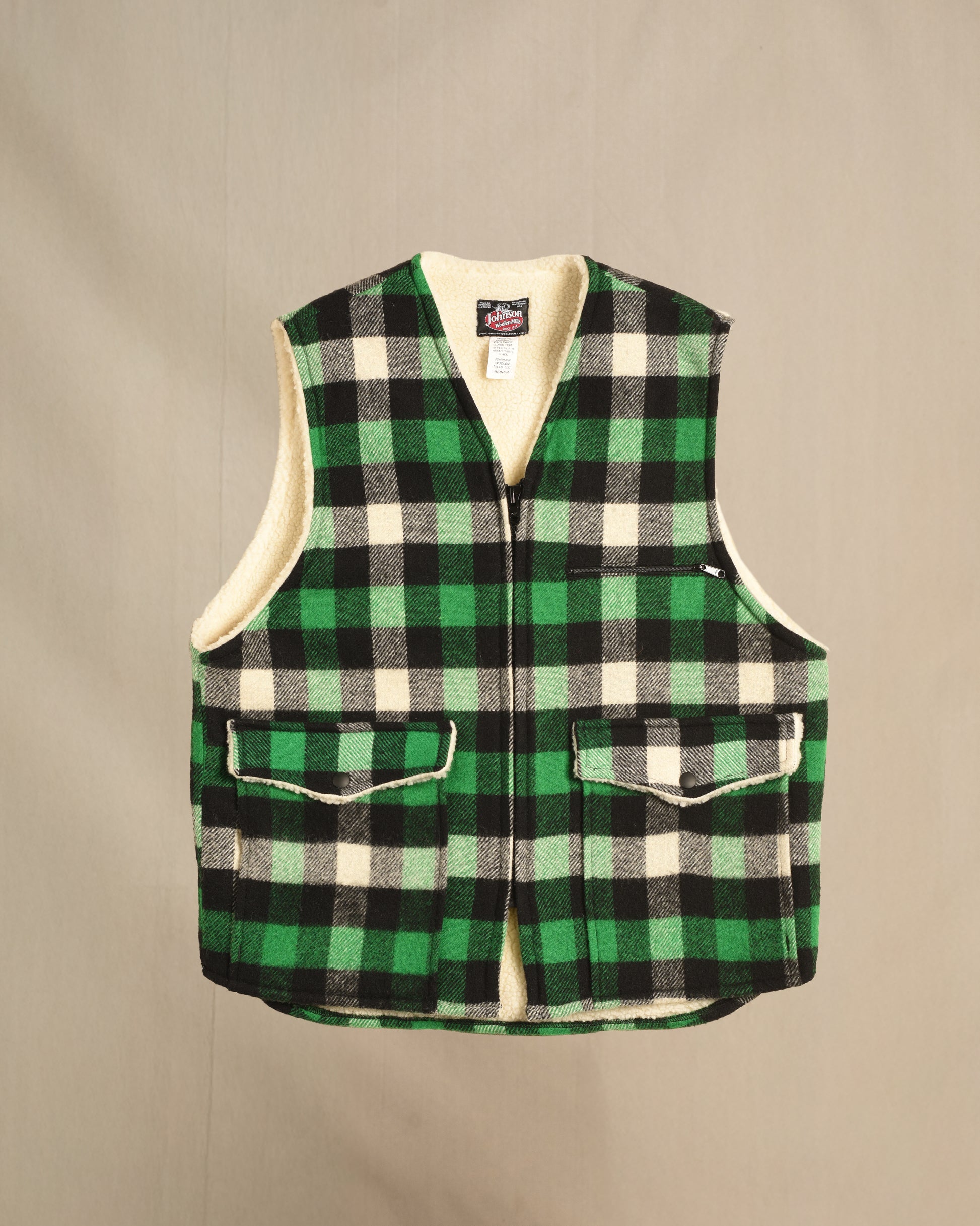 Green and black checkered sherpa vest on a beige background