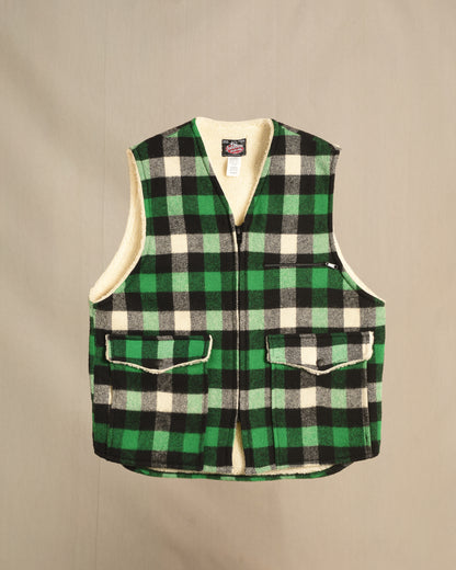 Green and black checkered sherpa vest on a beige background