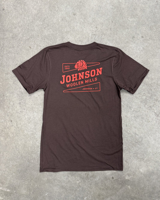 Brown t-shirt with red 'Johnson Woolen Mills' logo on a gray concrete surface
