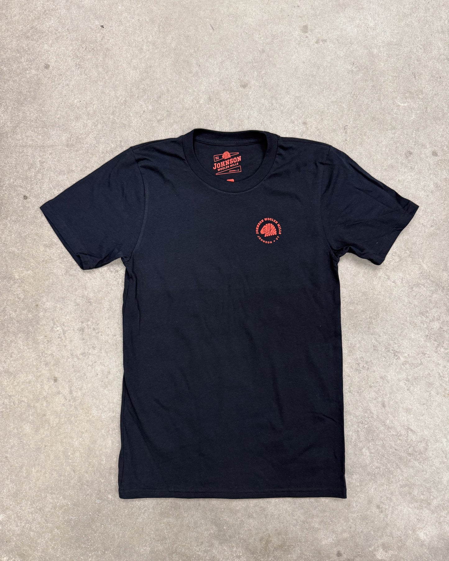 Black t-shirt with a red logo on a gray concrete surface