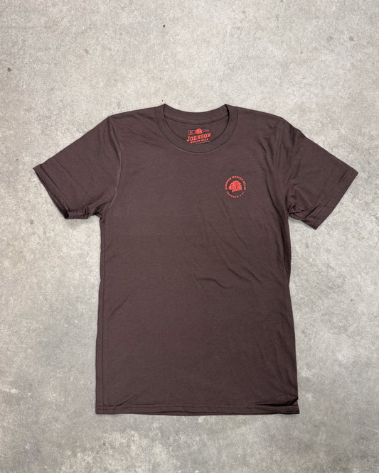 Brown t-shirt with a red logo on a gray concrete surface
