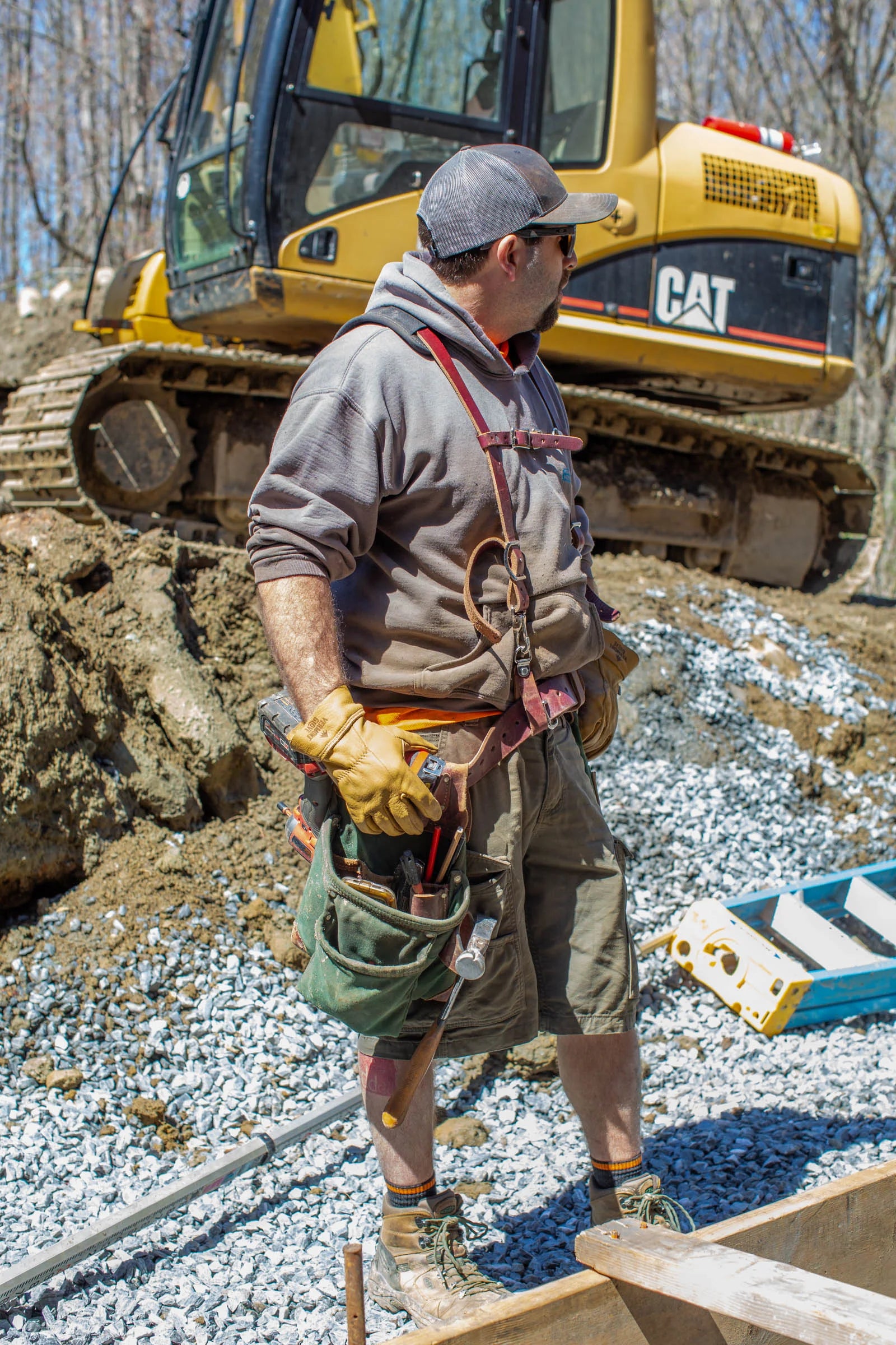 Man working on a construction site with a Caterpillar excavator in the background