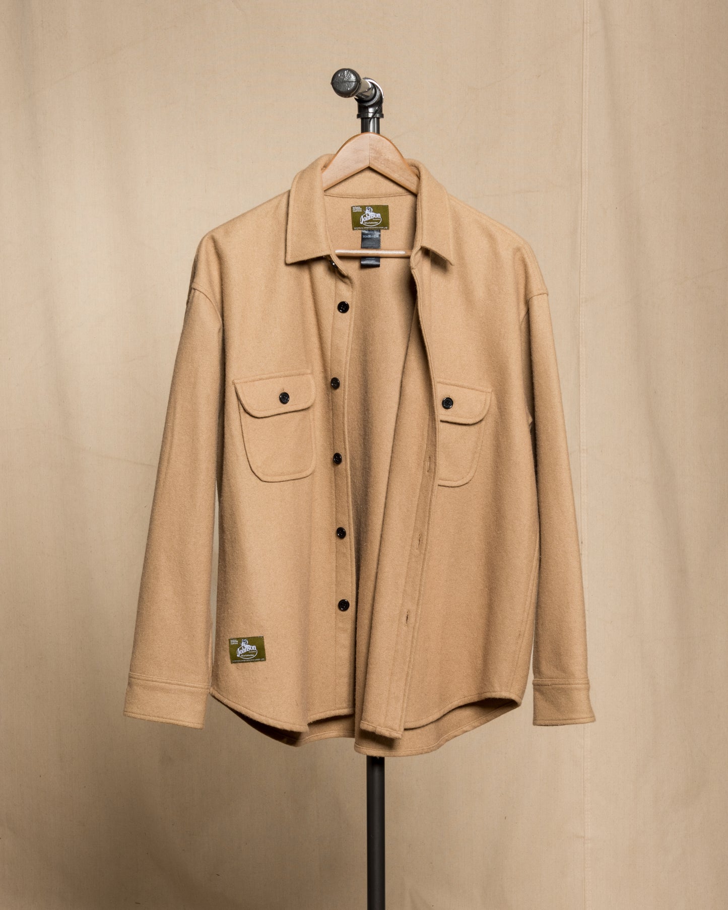 tan wool button down shirt hanging from black steel pipe