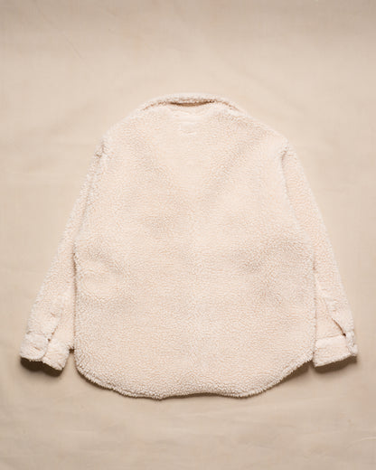 A cream-colored sherpa fleece jacket shown from the back, laid flat on a matching beige textured background.