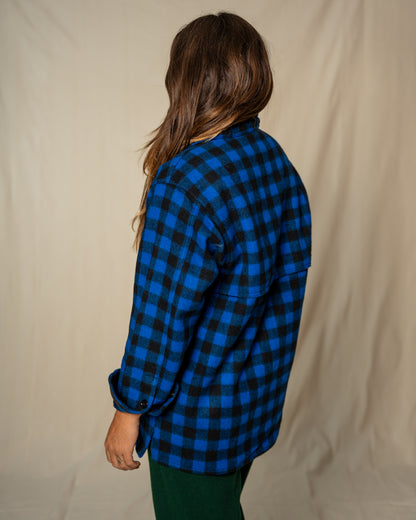 Person wearing a blue and black checkered shirt against a beige background