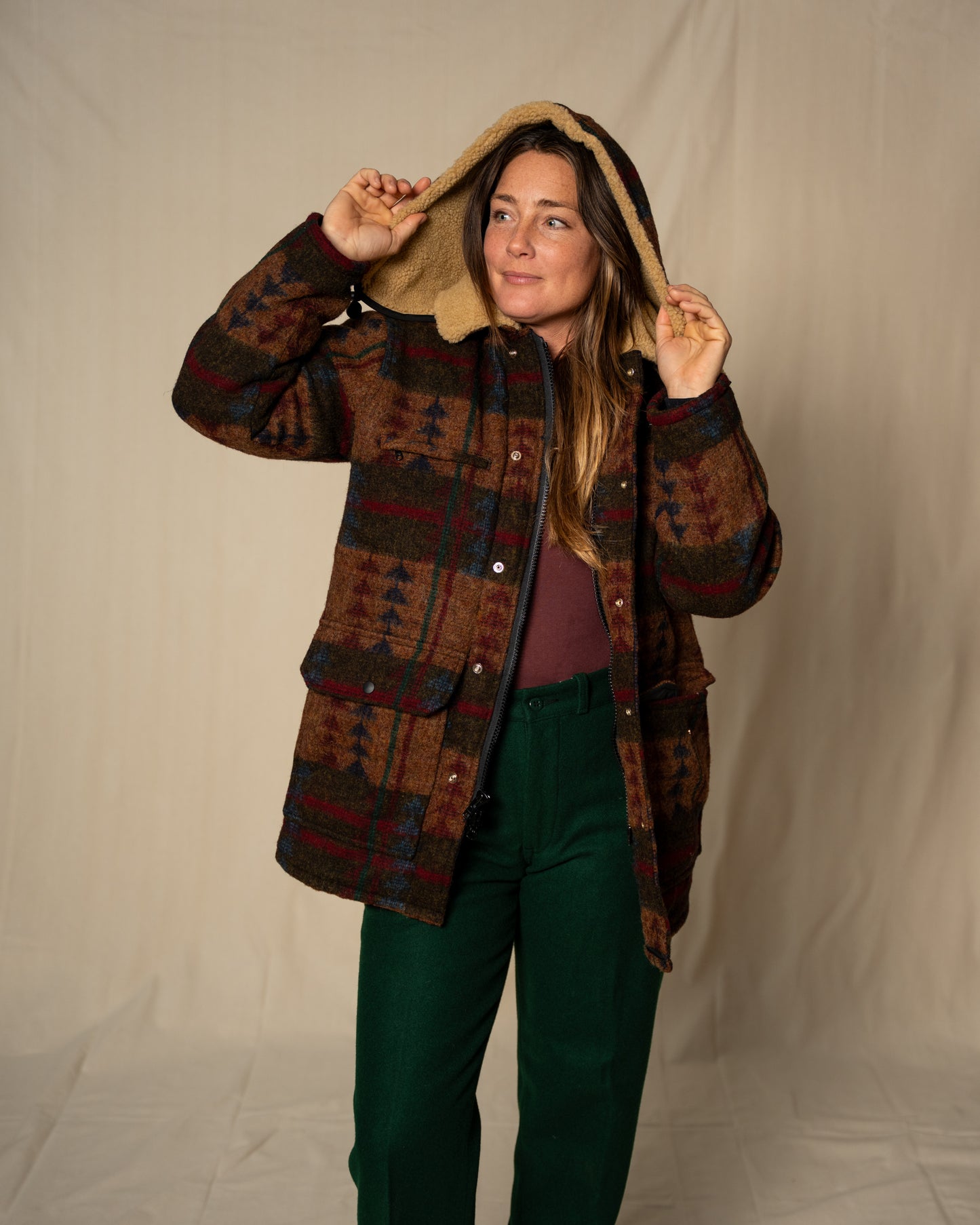 Person wearing a patterned jacket with a hood against a plain background