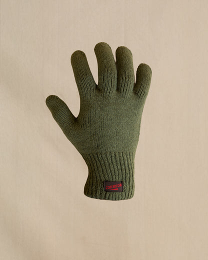 A single knit merino wool glove in olive green. The glove has a small brown and  red Johnson label on the cuff. 