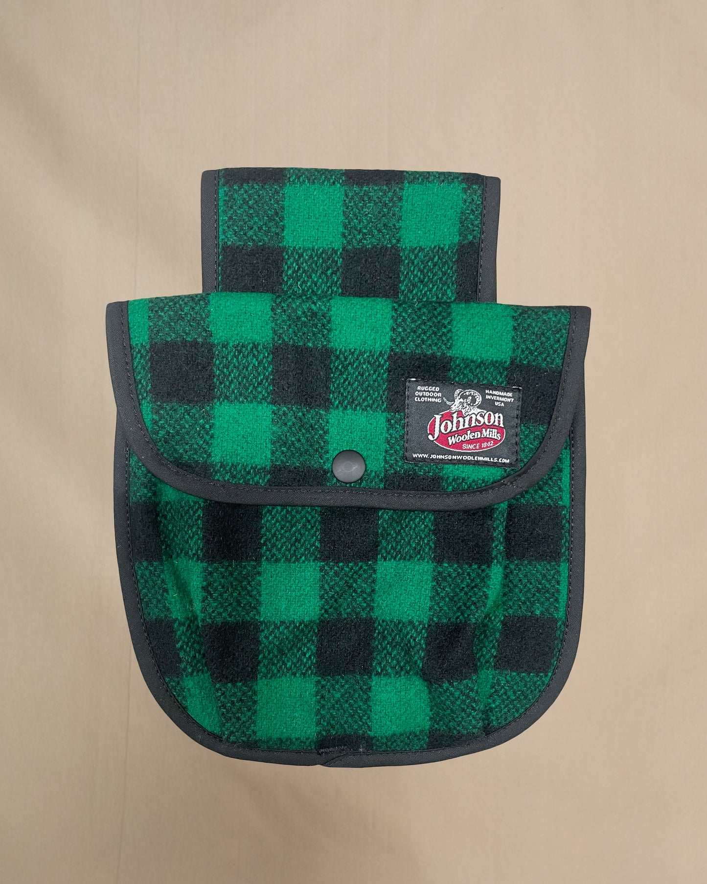 Green and black checkered black powder pouch with a Johnson logo on a beige background