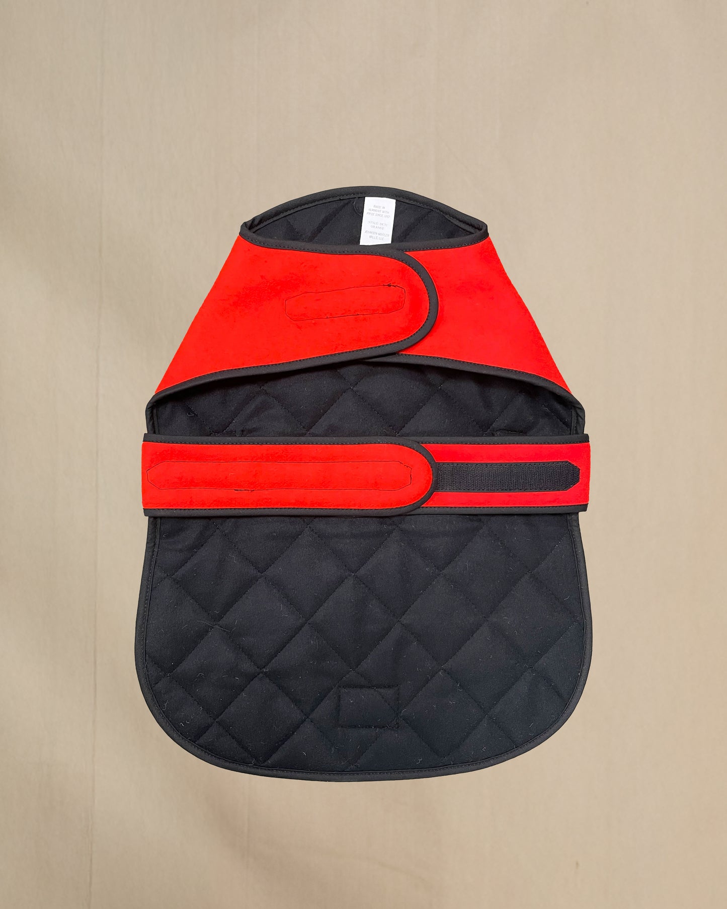 Blaze orange dog coat with quilted lining on a beige background