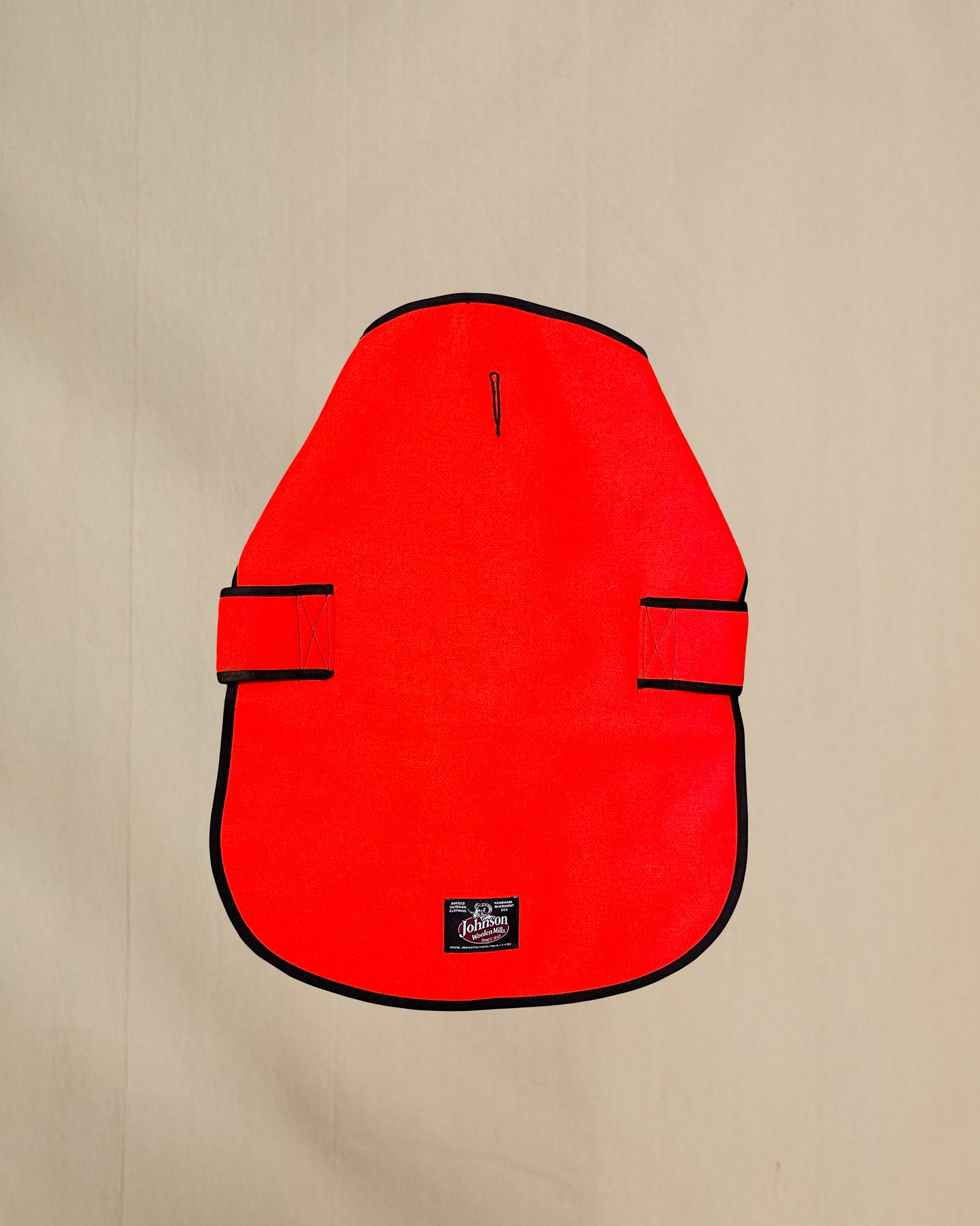 Blaze orange wool dog coat with black trim on a beige background