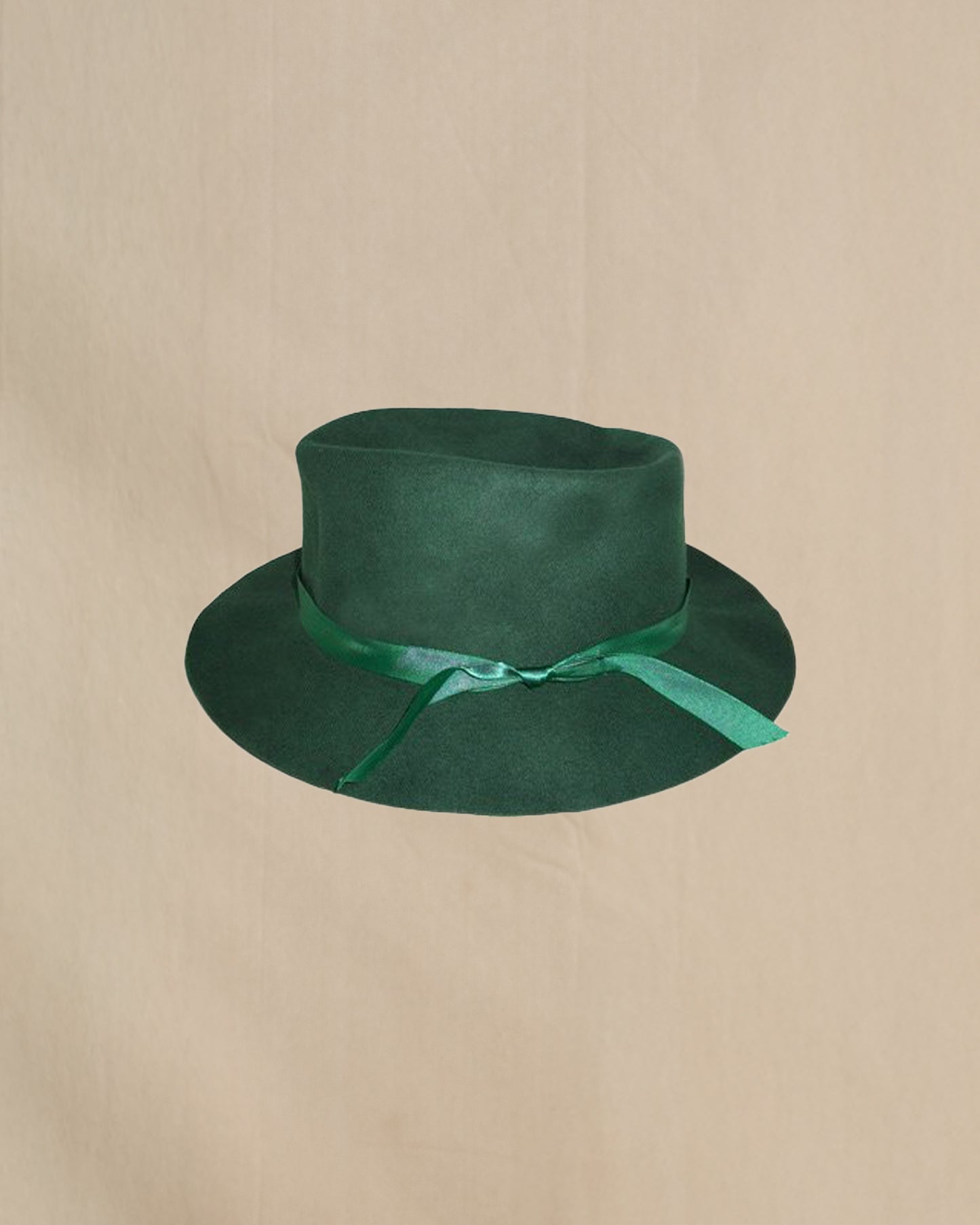 Green hat with a ribbon on a beige background