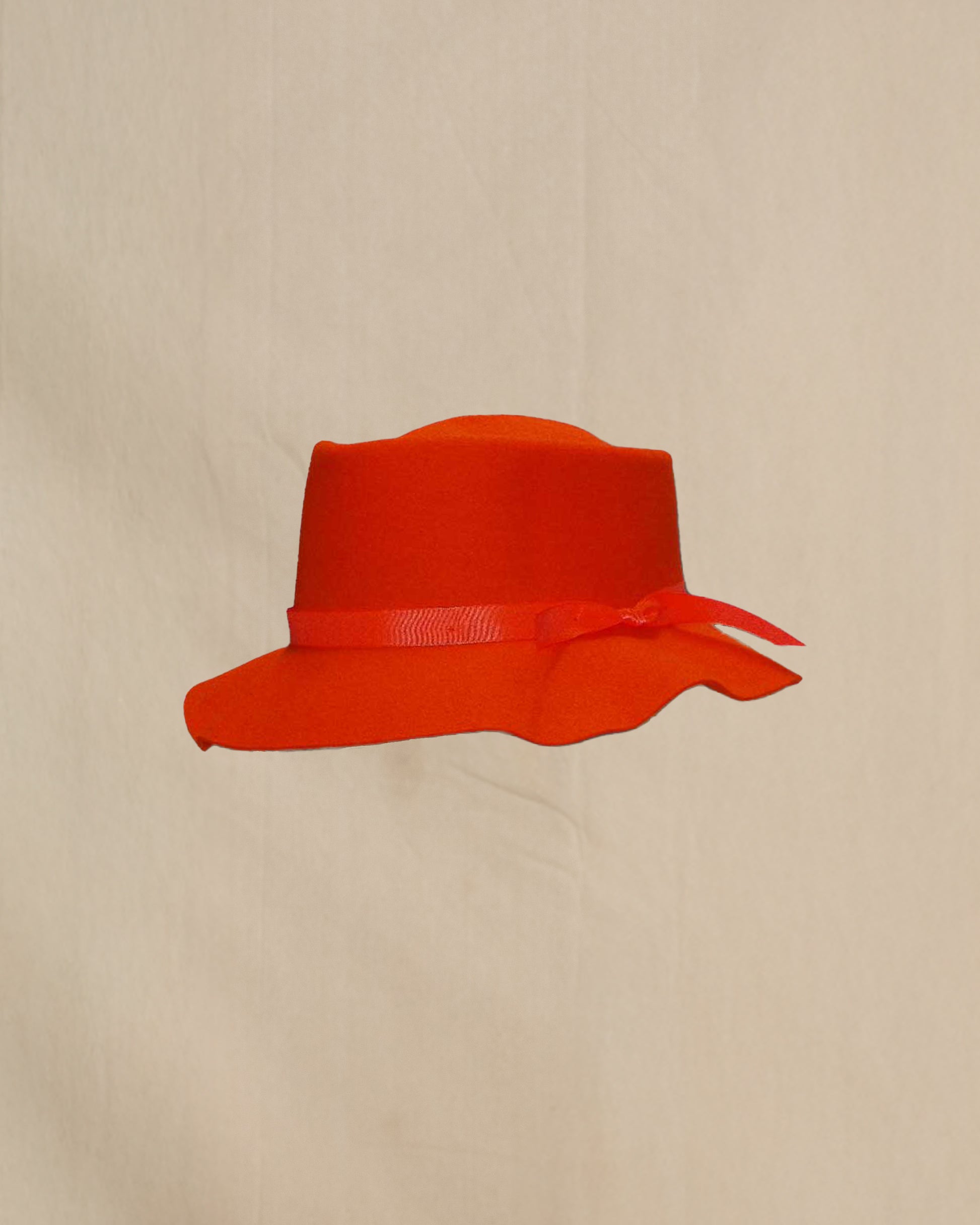 Orange hat with a ribbon on a beige background