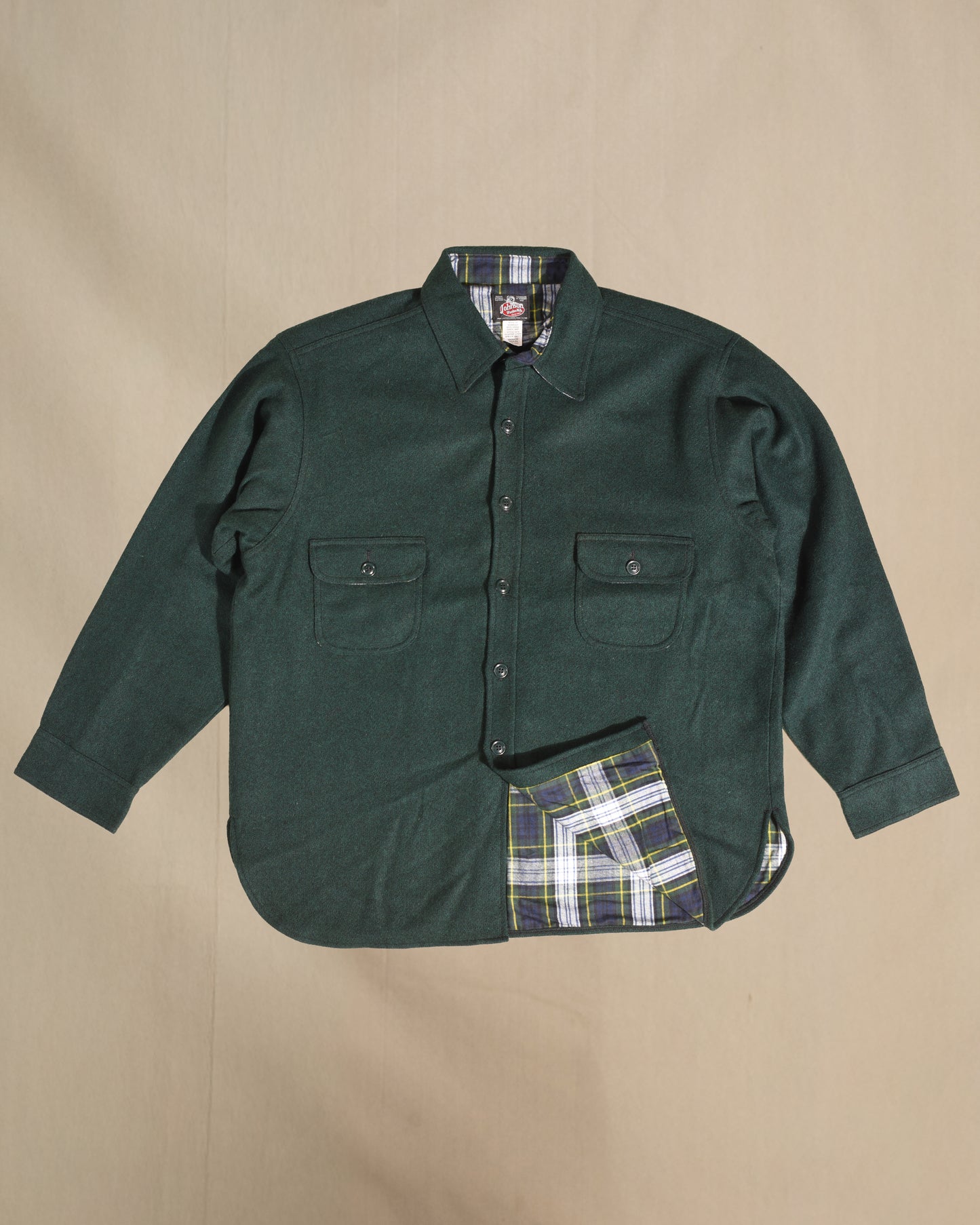 Green shirt with blue and white plaid lining on a beige background