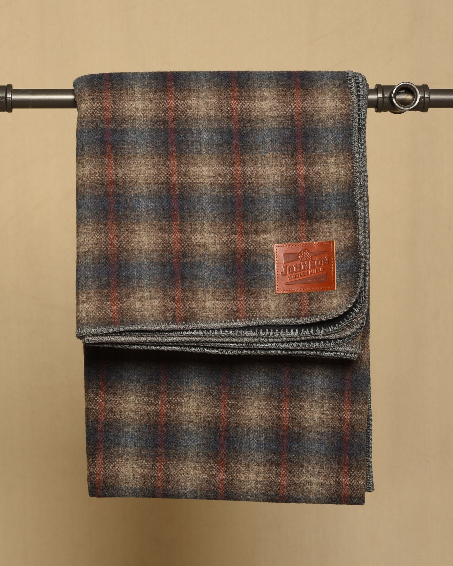Gray and blue Plaid blanket with a leather Johnson label on a beige background
