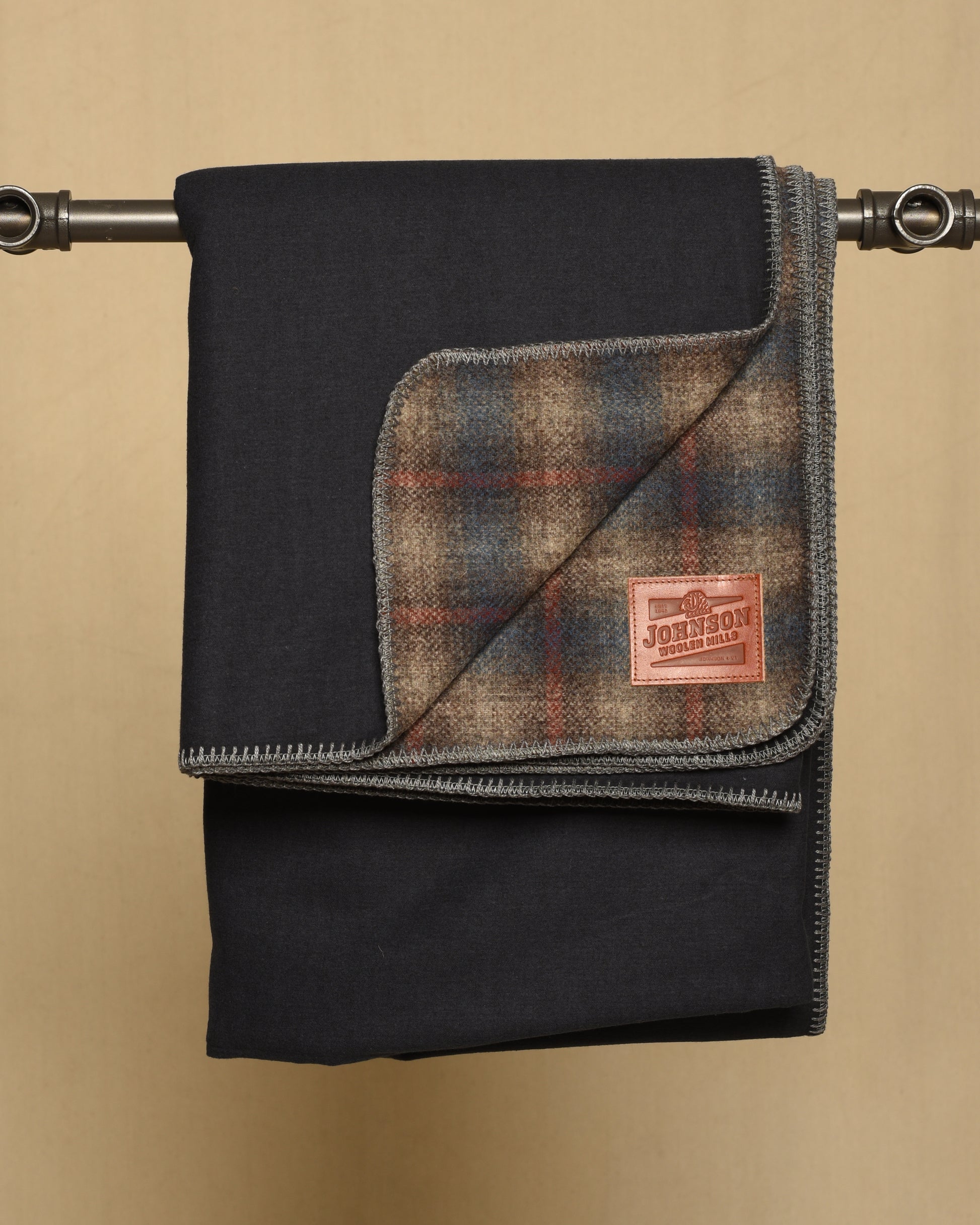 Gray and blue Plaid blanket with a leather Johnson label on a beige background