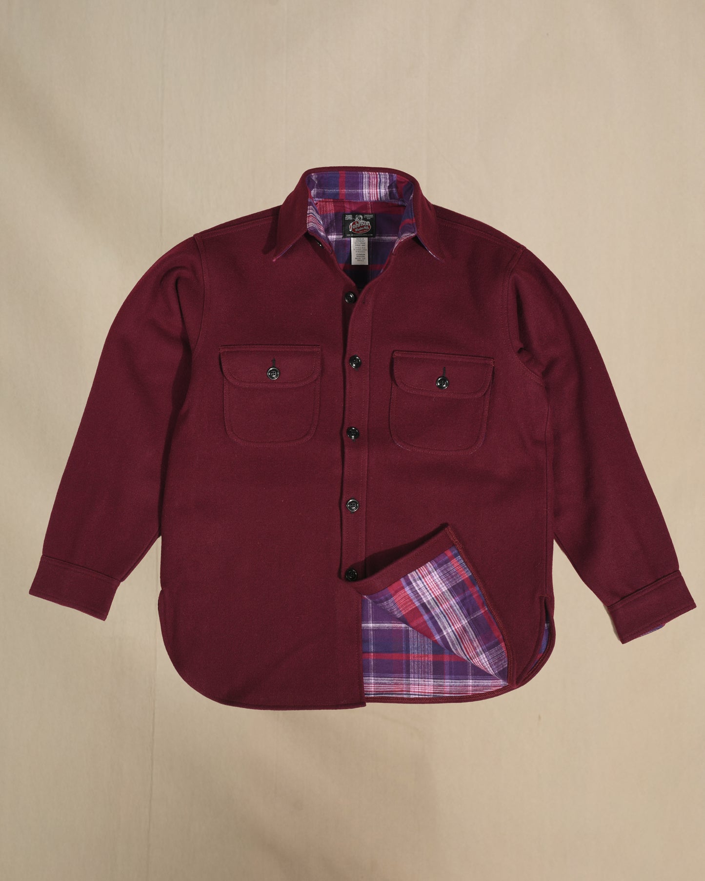 Burgundy shirt with purple plaid lining on a beige background