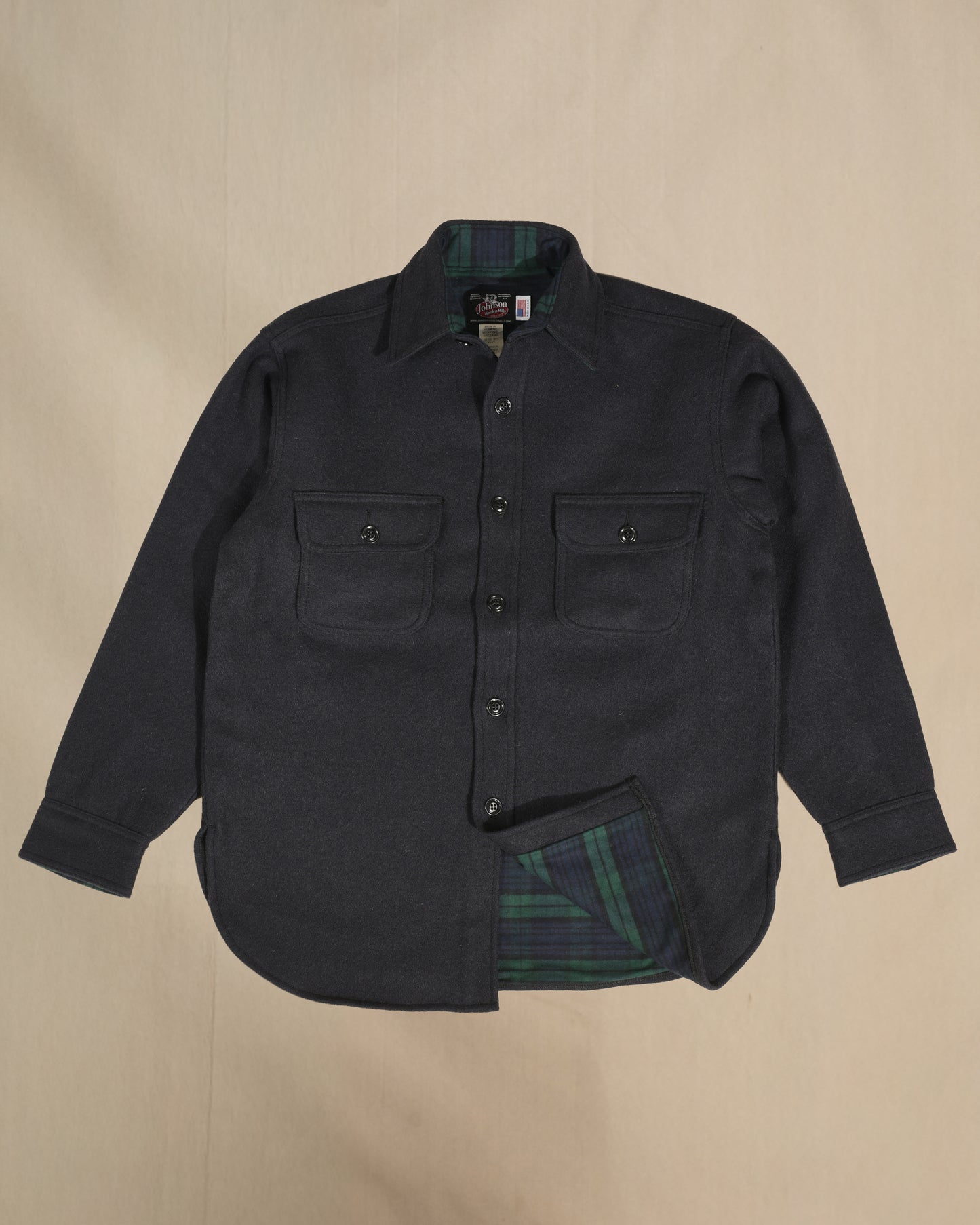 Black wool shirt with black watch plaid lining on a beige background