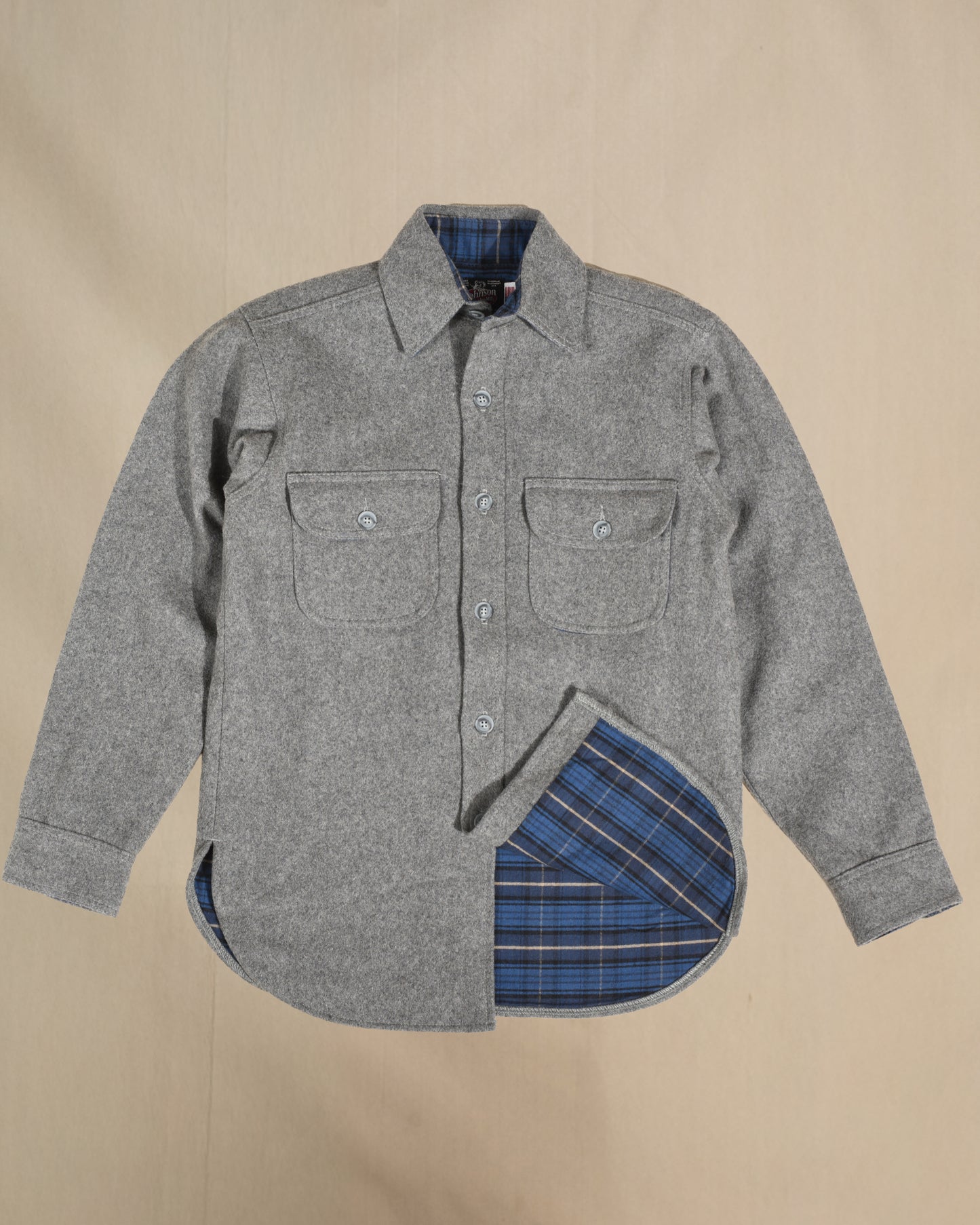 Gray flannel shirt with plaid lining on a beige background