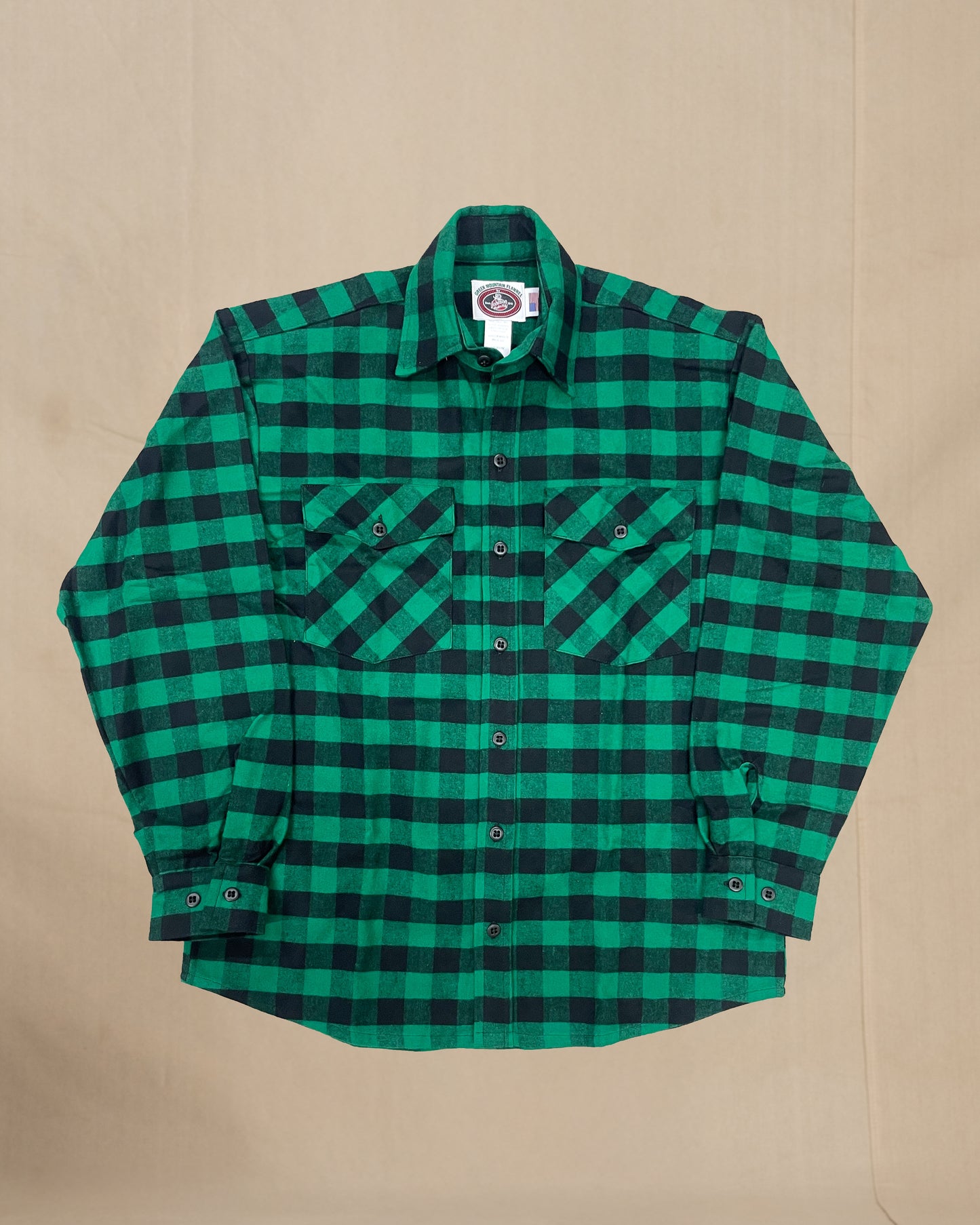 Green and black checkered flannel shirt on a beige background