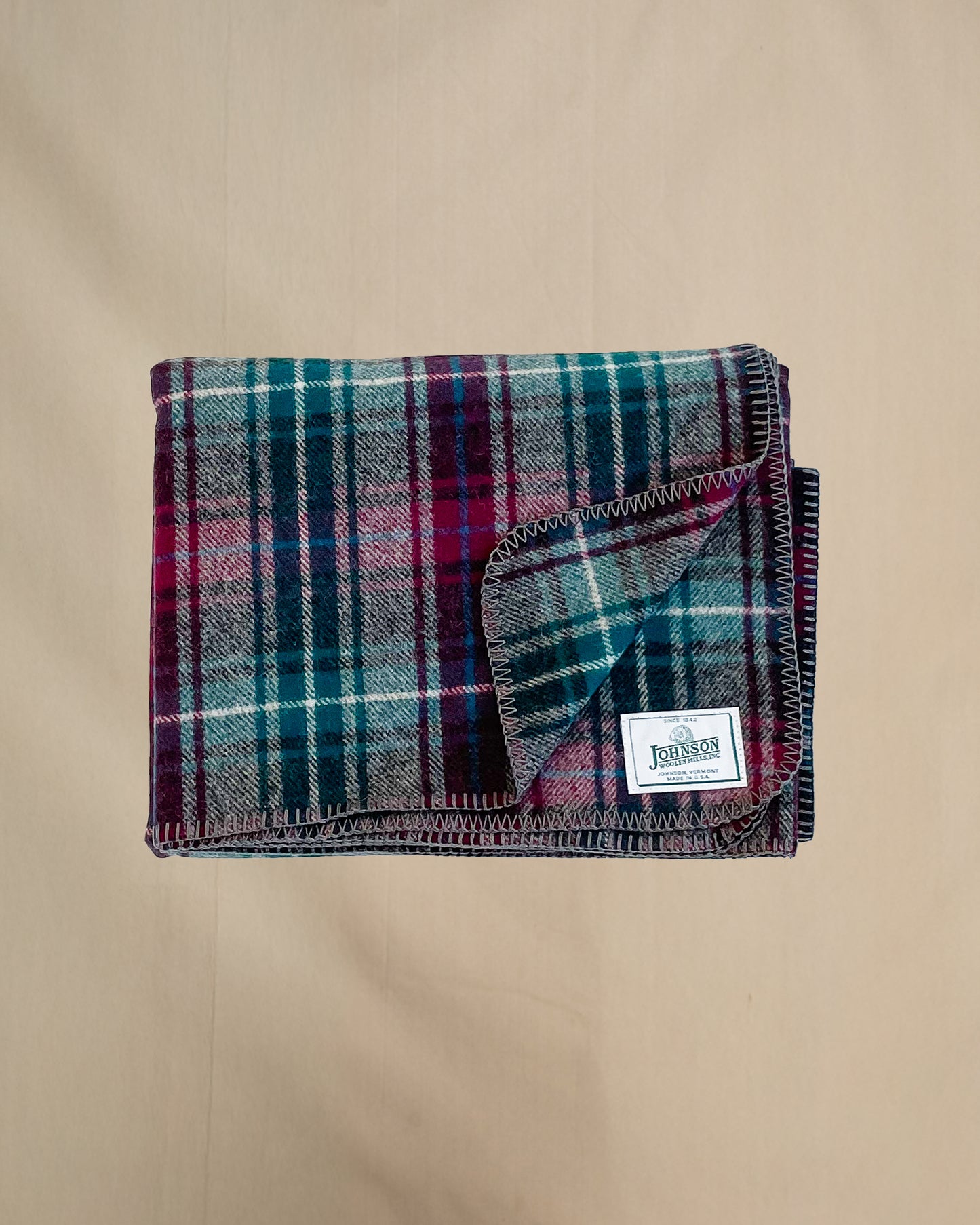 Johnson Woolen Mills Wine Gray Teel Plaid folded blanket showing logo patch